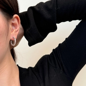 Detail of S925 silver hoop earrings with baguette-cut zircons worn by a model