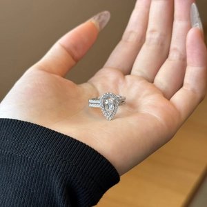Close-up of S925 sterling silver halo pear-cut ring set with stacked diamond bands
