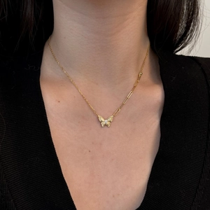 Asymmetrische gouden ketting met vlinderhanger en zirkoon op een zwarte trui gestyled