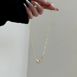 Detailopname van gouden vlinderketting met asymmetrische paperclipketting en heldere zirkoon