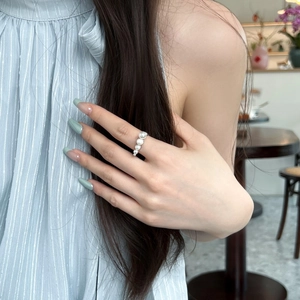 Close-up of five white pearls in gradient sizes on a silver S925 band worn by a model
