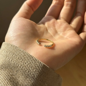 Detailed view of an open golden ring with sparkling cubic zirconia on a hand