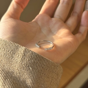 Close-up of S925 sterling silver open ring with pavé diamonds held in hand