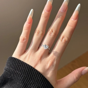 Close-up of a large heart-shaped diamond solitaire ring on model's hand with silver band