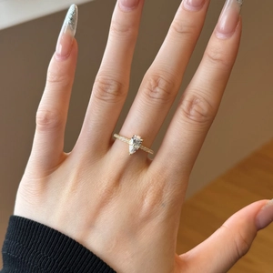 Close-up of a pear-shaped gold ring with pavé diamonds worn on a woman's finger