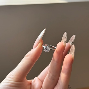 Detailed view of a silver solitaire engagement ring with a round zircon on a model hand