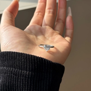 Macro shot of an elegant heart-shaped solitaire diamond ring on palm under natural light