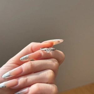 Close-up of a heart-shaped diamond ring on a model's finger with silver band