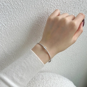 Macro shot of silver bangle with emerald-cut zirconia and micro-pave setting on wrist