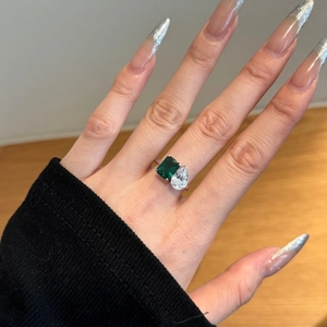 Détail d'une bague en argent S925 avec pierre émeraude verte et gemme claire en poire