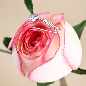 Detailed view of silver Mom brooch with heart-shaped zircon on pink rose petals