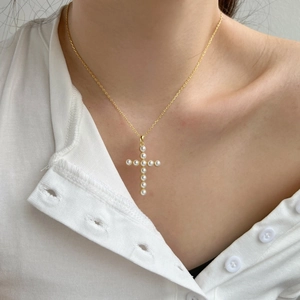 Detailed view of S925 silver cross pendant with white pearls on a gold chain