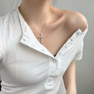 Gros plan d'un collier croix en argent S925 doré avec zircons sur le cou d'une femme