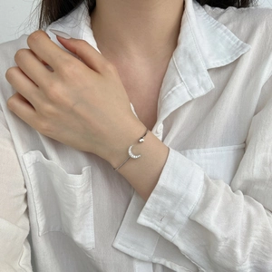 Macro shot of S925 sterling silver moon bracelet with zircon pavé on female wrist