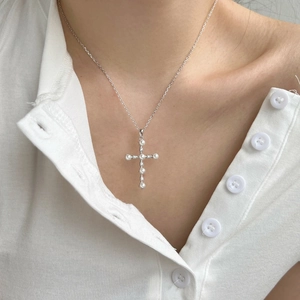 Dettaglio del ciondolo a croce in argento S925 con perle e zirconi sulla modella