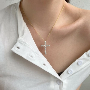Vue macro d'un pendentif croix en argent doré avec oxydes de zirconium sur cou