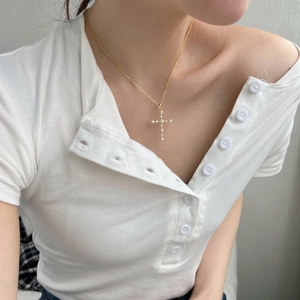 Vista dettagliata di un'elegante collana a croce in argento S925 dorato con perle su modella