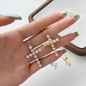 Close-up of gold and silver S925 cross necklaces with elegant inlaid pearls for women
