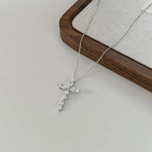Détail macro du pendentif croix en argent avec zircons sur une chaîne délicate