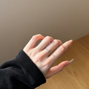 Close-up of a heart-cut diamond ring on a hand wearing a black sweater