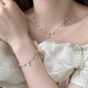 Detailed view of silver clover necklace and bracelet set with sparkling zircon stones