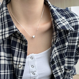 Close-up of minimalist S925 sterling silver heart pendant necklace on female model