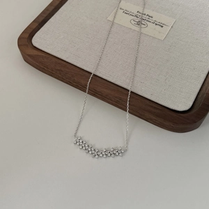 Vue macro d'un collier en argent S925 avec fleurs en zircon sur fond de lin