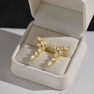 Vue macro de boucles d'oreilles géométriques en zircon dans un écrin beige