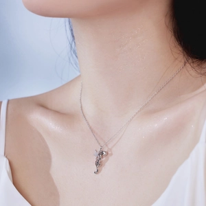 Close-up of a silver S925 seahorse and shell pendant with sparkling crystals on a chain