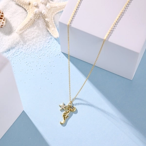Close-up of gold nautical necklace with starfish, seahorse and shell charms on blue beach decor
