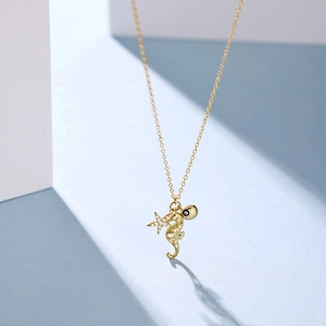 Close-up of golden seahorse, starfish and shell ocean pendants on a fine gold chain