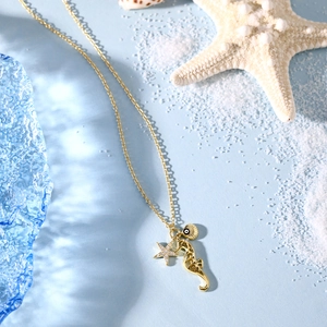 Detail of gold ocean necklace with seahorse, diamond starfish, and evil eye shell charms