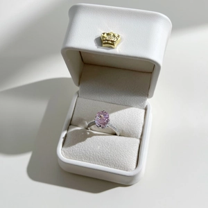 Macro shot of oval pink gemstone ring in a white crown gift box for engagement