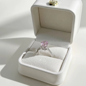 Detailed side view of an oval pink zircon ring with micro-pave diamonds in a white box