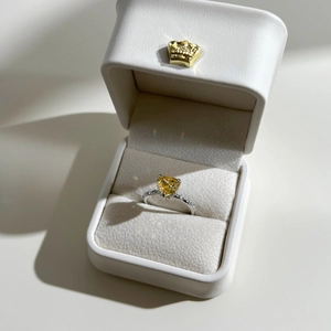 Détail d'une bague coeur en zircon jaune et anneau argenté dans un coffret cadeau