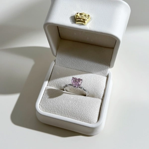 Vue détaillée d'une bague coeur rose en zircon dans son écrin blanc à couronne