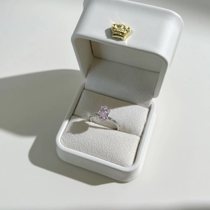 Detailed shot of an oval pink zircon ring with pavé side stones in a crown gift box