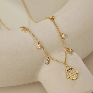 Collier Main de Fatma doré avec oeil bleu maléfique et zircons blancs sur support