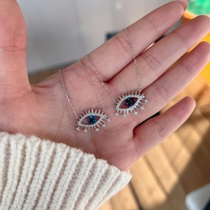 Détail de pendentifs œil bleu en argent avec accents d'étoiles sur les cils