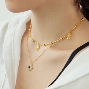 Close-up of gold layered S925 silver necklace with Evil Eye and Hamsa Hand charms on neck