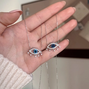 Colliers œil protecteur en argent 925 avec zircon bleu tenus à la main