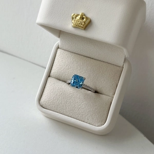 Detailed macro of a square-cut blue zircon ring in a premium crown jewelry box