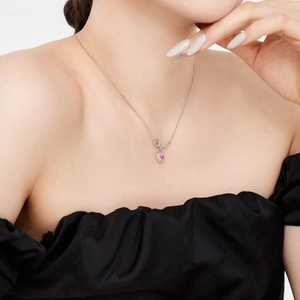 Gros plan du collier en forme de cœur rose avec nœud élégant sur la clavicule