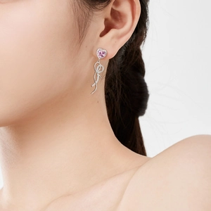 Gros plan sur la boucle d'oreille cœur rose avec ruban en argent poli et zircon