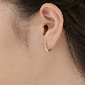 Close-up of gold S925 sterling silver huggie earrings with sparkling cubic zirconia stones