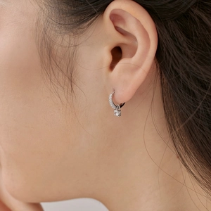 Détail macro de créoles en argent S925 serties de zircons et pendentif en pierre brillante