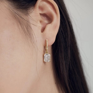 Close-up of a model wearing a gold hoop earring with a square-cut ice flower zircon
