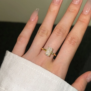 Detailed view of rectangle cut zircon ring in gold finish on a model's finger