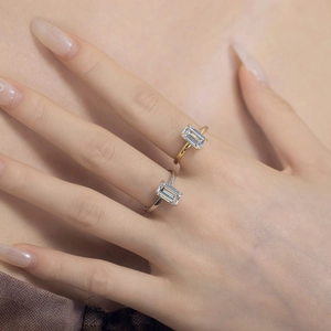 Close-up of emerald-cut zircon rings in gold and silver finish worn on fingers