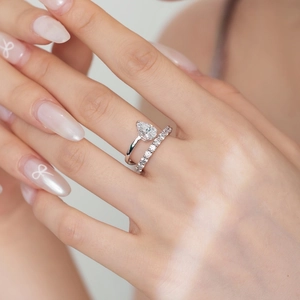 Close-up of a pear-cut zircon solitaire ring stacked with a classic eternity band in silver